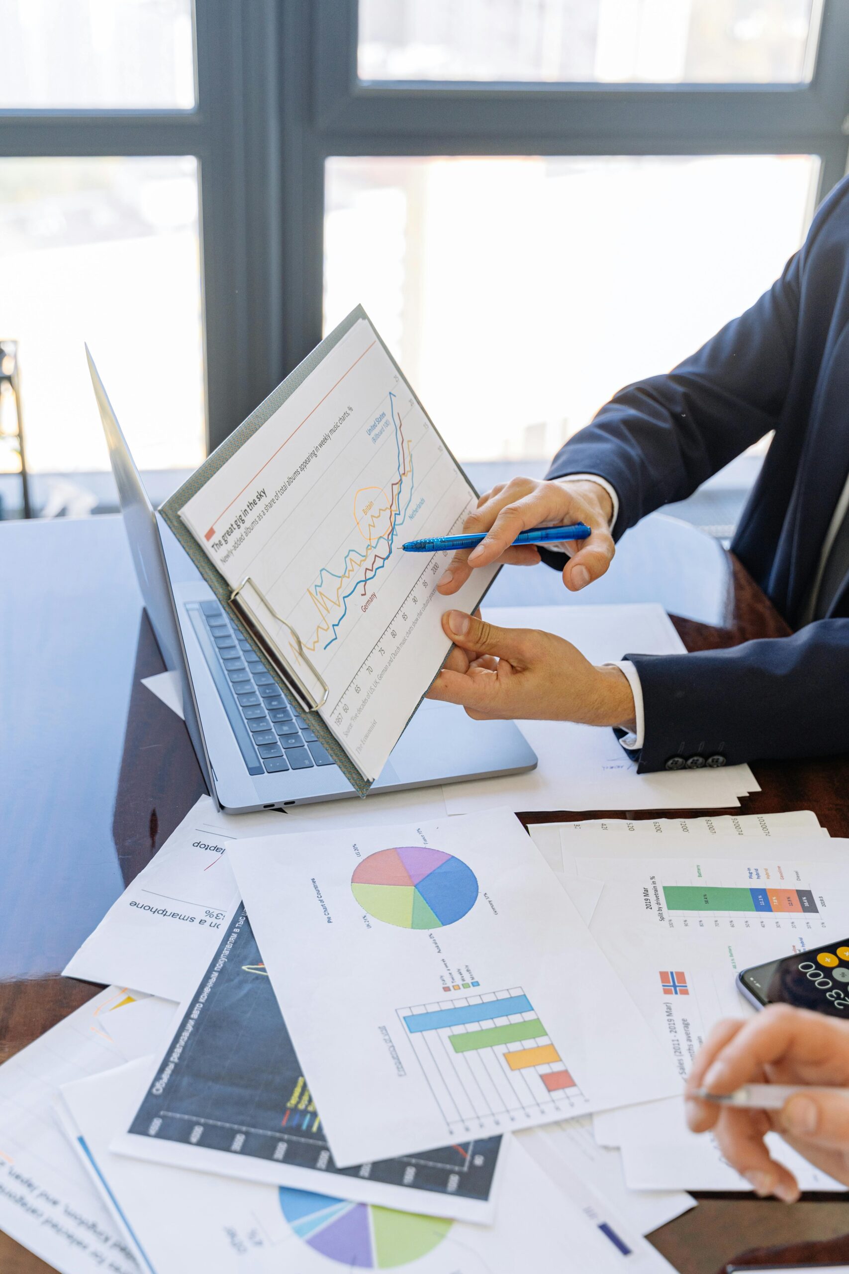 Free Business professionals discussing financial graphs and charts in an office setting. Stock Photo Photo by Antoni Shkraba Studio: https://www.pexels.com/photo/person-in-black-suit-jacket-holding-white-paper-5816299/